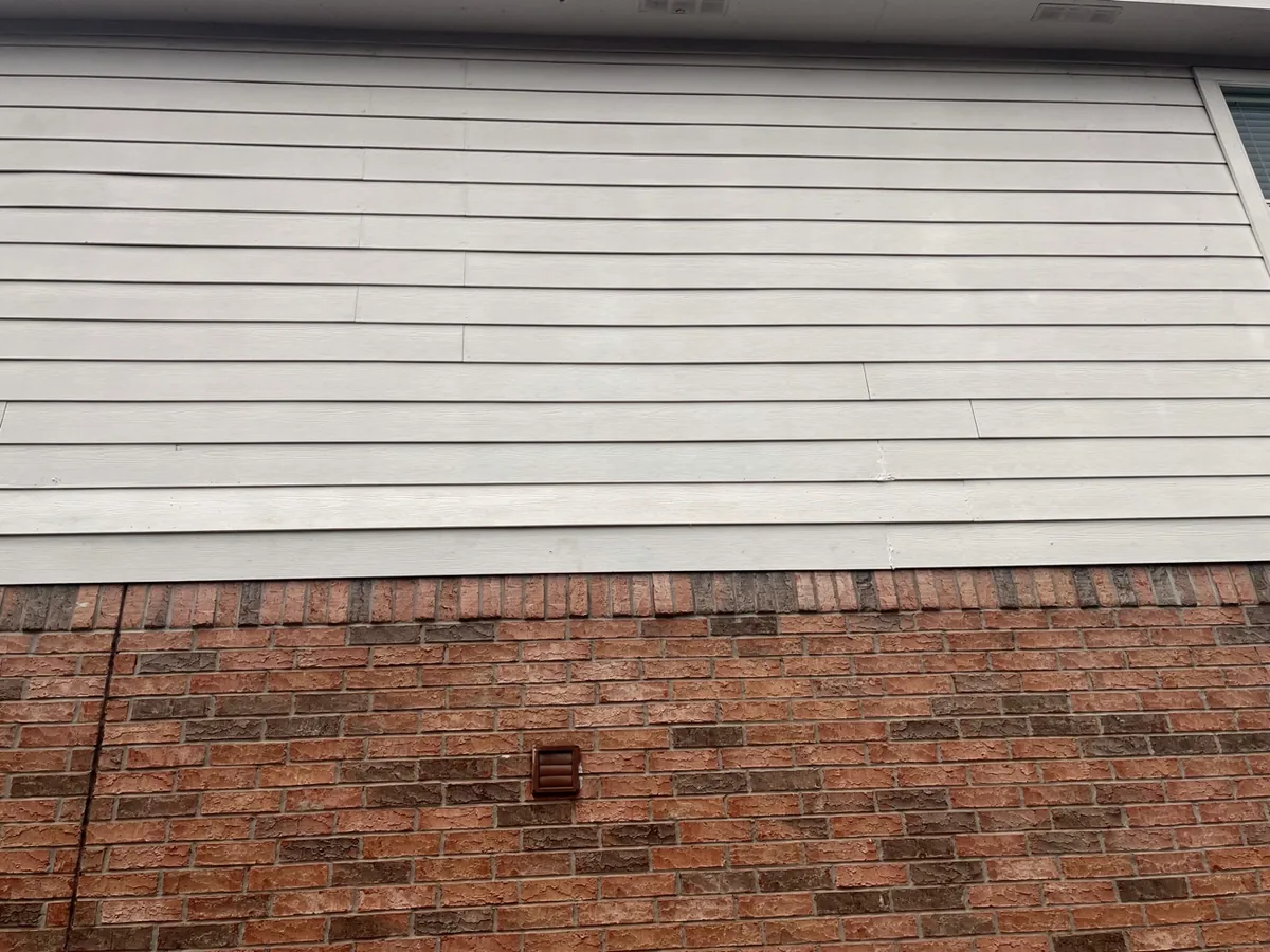 Finished siding repair with new boards painted white, blending with the existing wall